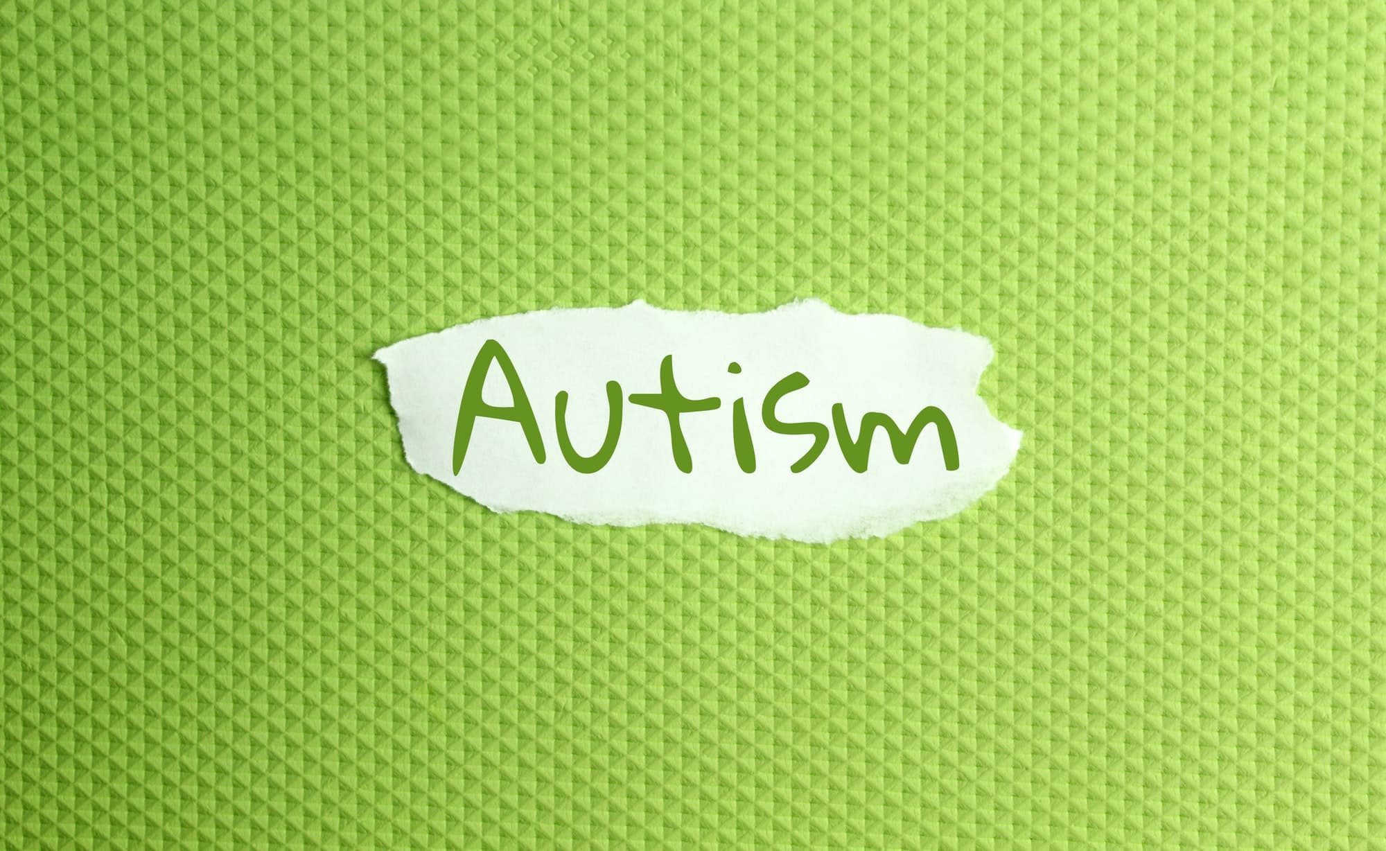 una carta strappata scritta con l'iscrizione autismo su uno sfondo verde