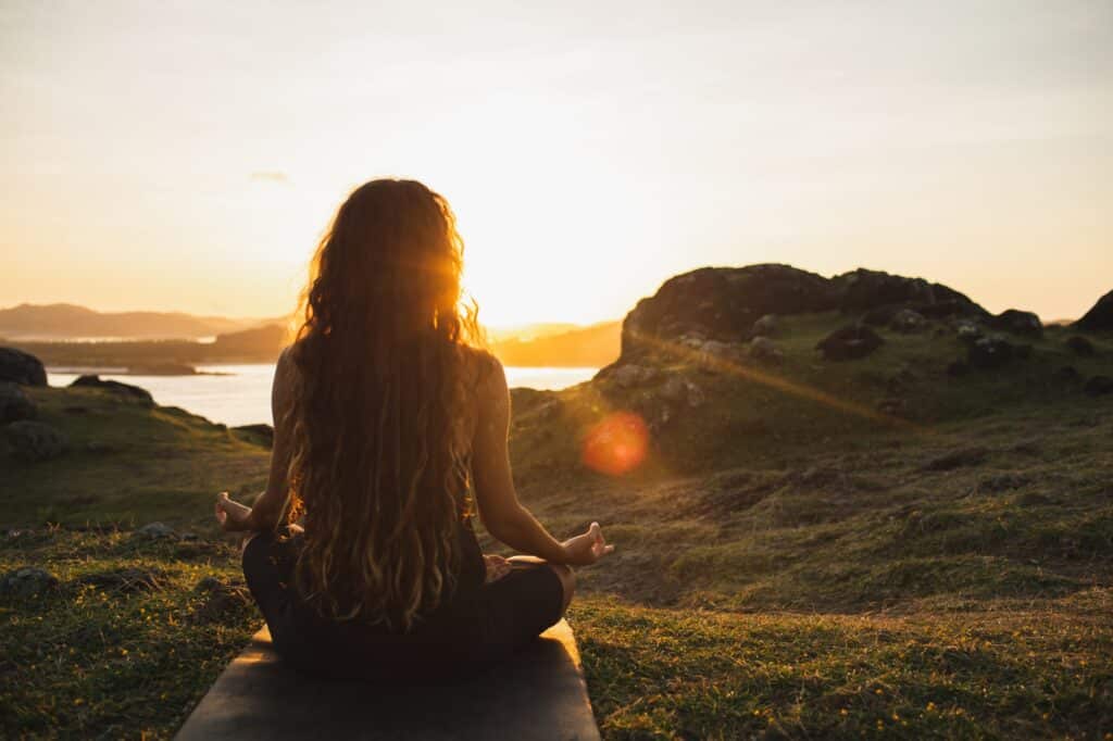 Donna che medita yoga da sola all'alba montagne. Vista da dietro. Viaggio Stile di vita Spirito
