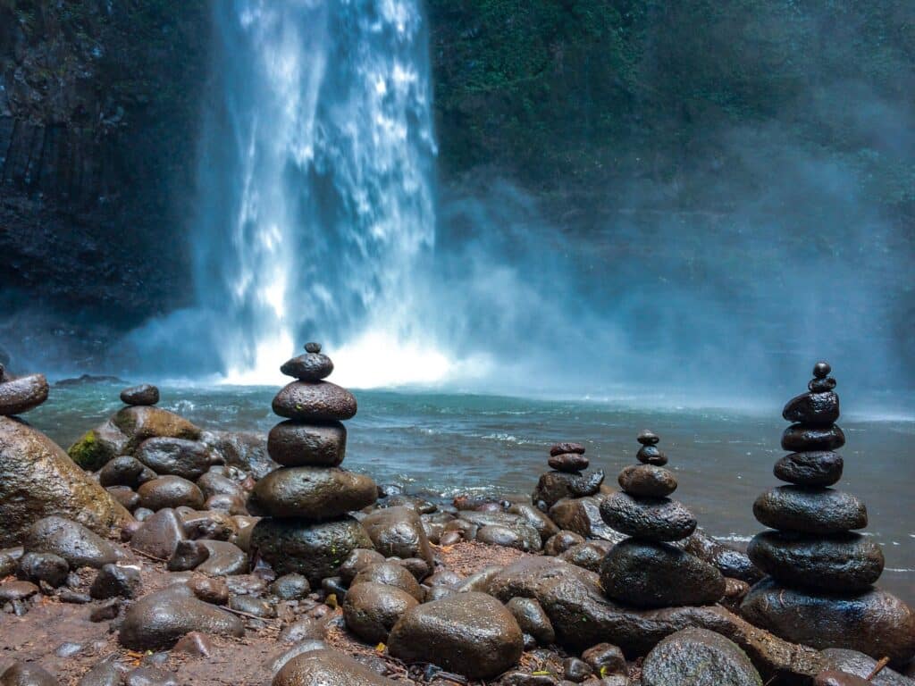 Pietre impilate per la meditazione davanti a una cascata blu nella giungla